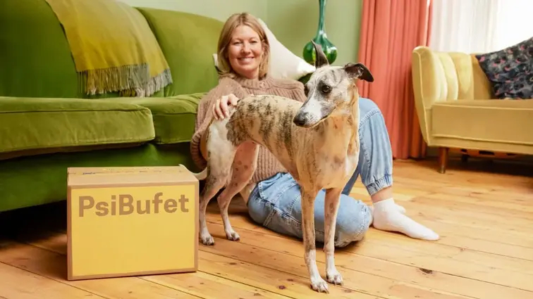 Žena sedící na podlaze se psem vedle krabice PsiBufet.