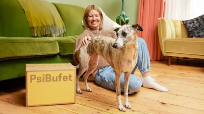 Žena sedící na podlaze se psem vedle krabice PsiBufet.